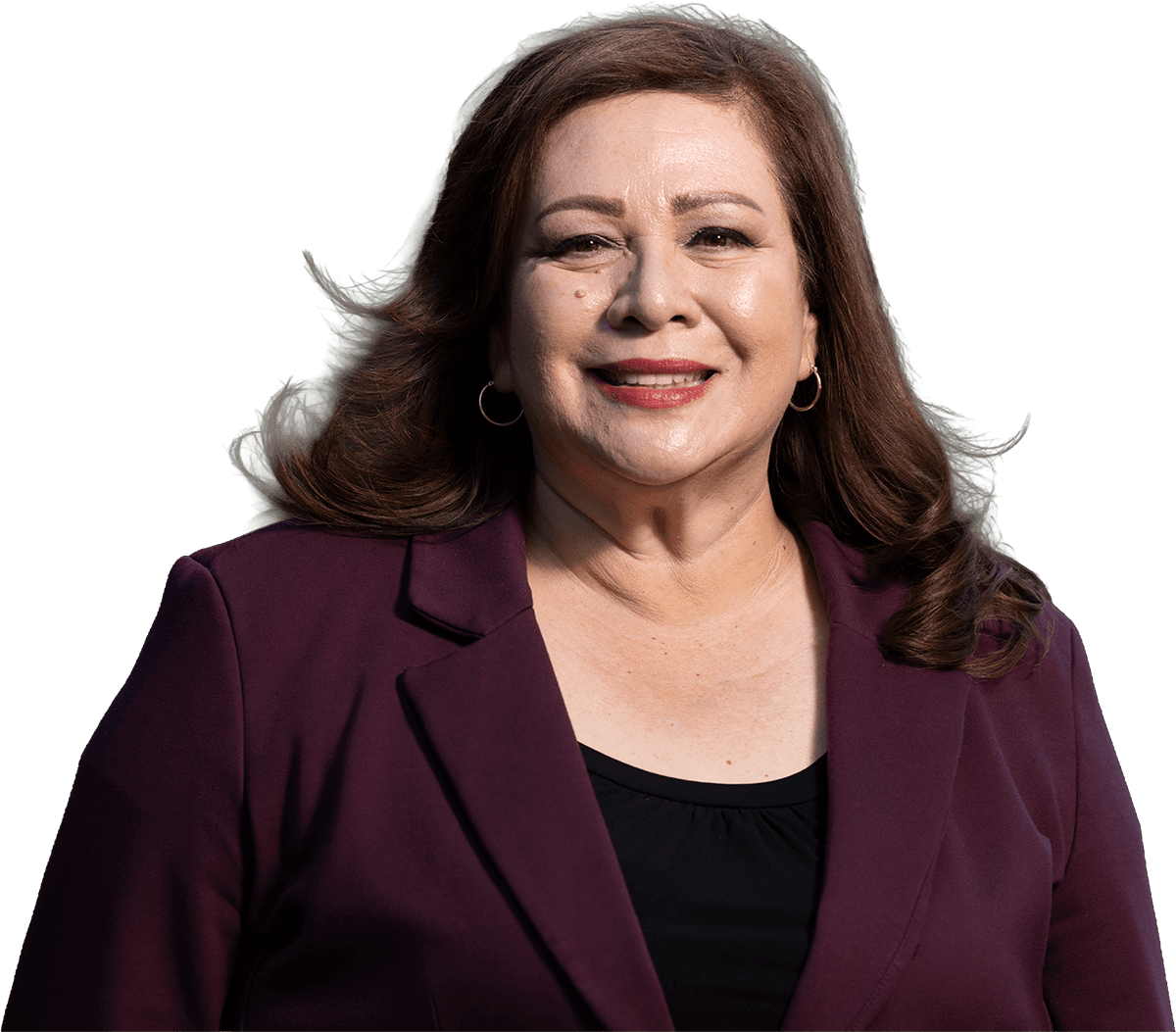 Portrait of Sandra Armenta smiling outdoors, wearing a burgundy blazer over a black top with trees softly blurred in the background.